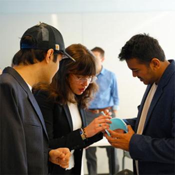 miips students gathered around a prototype during a capstone presentation